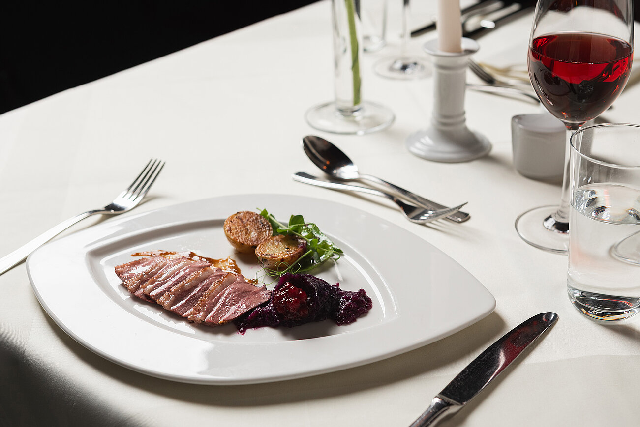 Gourmet-Entenbrust mit Bratkartoffeln, Rotkohl und Salat auf elegantem weißen Teller