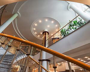 Moderne Treppe mit Metallgeländer und runden Deckenleuchten