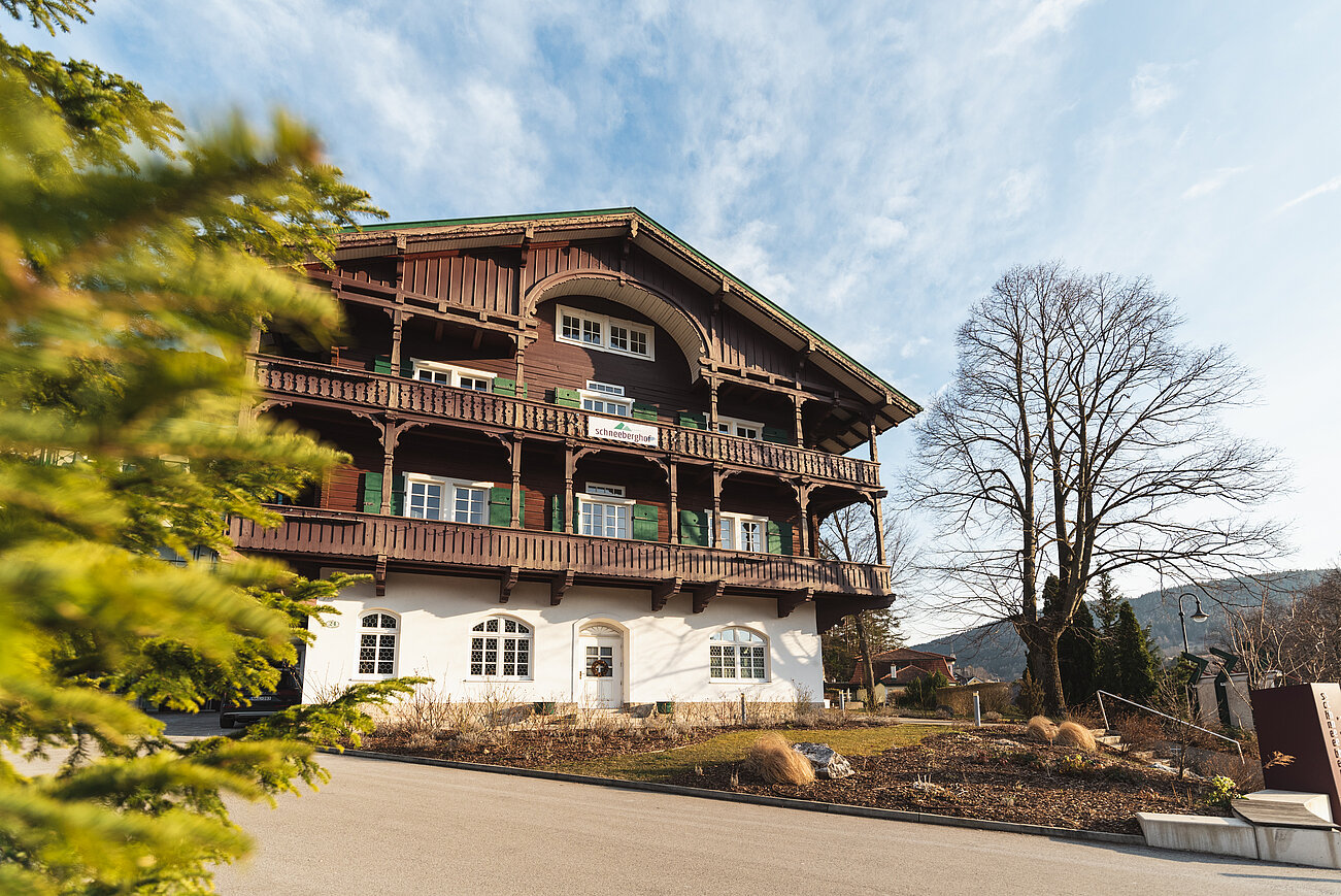 Traditionelles Alpenhotel Schneeberghof mit Holzbalkonen und grünen Fensterläden in Berglandschaft
