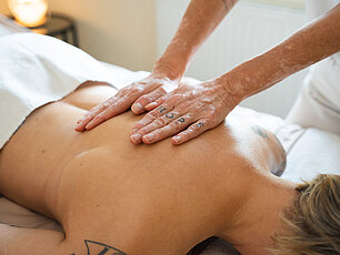 Entspannende Rückenmassage in einem Spa mit warmer Beleuchtung und professionellem Therapeuten