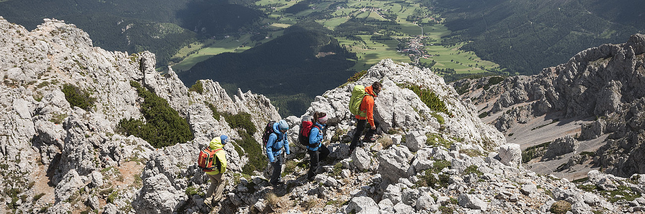 Wanderergruppe auf felsigem Bergpfad mit Panoramablick ins alpine Tal
