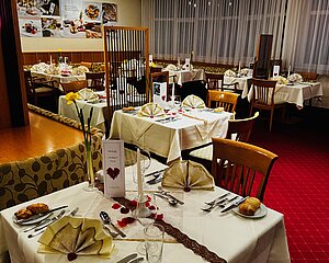 Eleganter Restaurantbereich mit für ein romantisches Dinner gedeckten Tischen und Rosenblättern