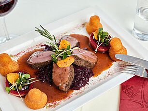 Gourmet-Hirschmedaillons mit Rotkraut, Soße, Herzoginkartoffeln und garnierten Rote-Bete-Scheiben