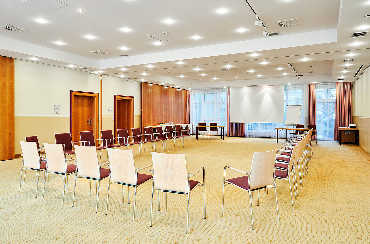 Leerer Konferenzraum mit Stühlen im Halbkreis vor einer Projektionsfläche angeordnet