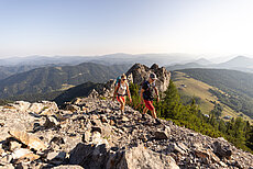 Zwei Wanderer auf felsigem Bergpfad mit weitem Bergblick