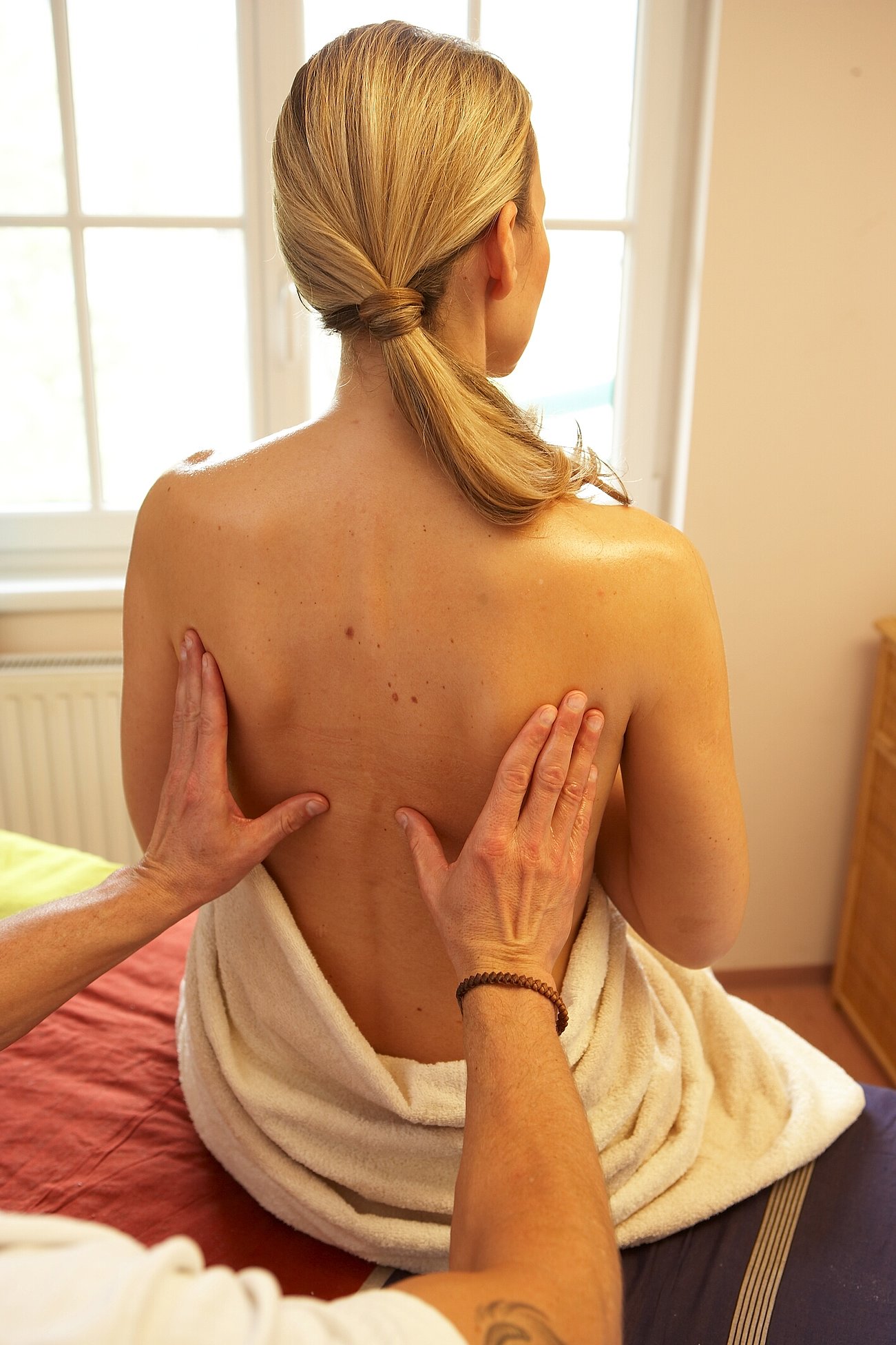 Frau erhält Rückenmassage im Spa, eingewickelt in ein weißes Handtuch