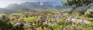Panoramablick auf alpines Dorf mit bunten Herbstbäumen und Bergkulisse