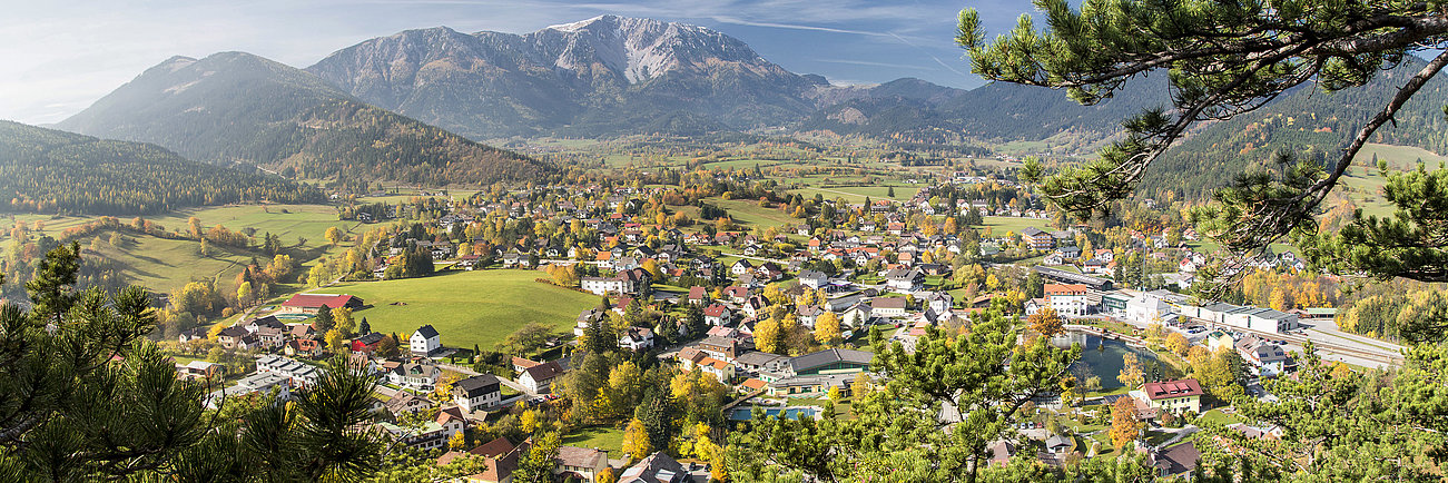 Panoramic view of Alpine village with colorful autumn trees and mountain backdrop