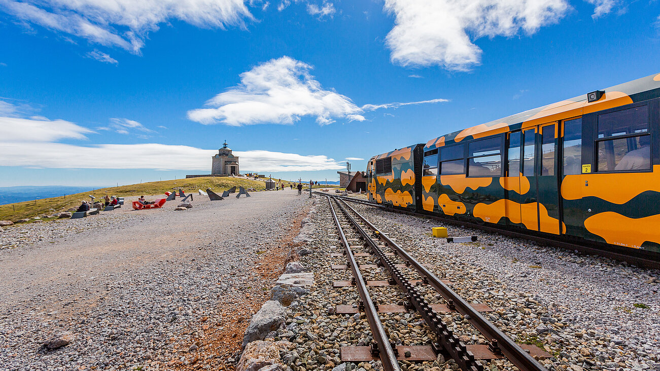 Bunter Gebirgszug an der Gipfelstation unter blauem Himmel mit Kapelle im Hintergrund
