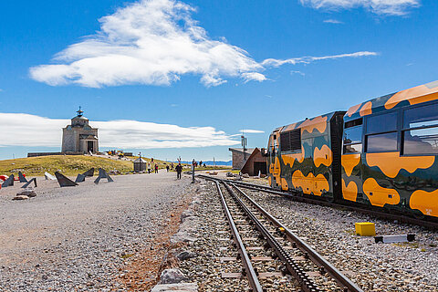 Bunter Gebirgszug an der Gipfelstation unter blauem Himmel mit Kapelle im Hintergrund