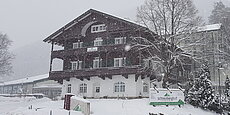 Verschneites Hotel Schneeberghof im winterlichen Wald bei starkem Schneefall