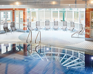 Innenbereich mit Spa-Pool, Liegestühlen und großen Fenstern bei Tageslicht