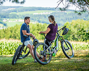 Paar mit E-Bikes macht Pause in einer idyllischen Landschaft