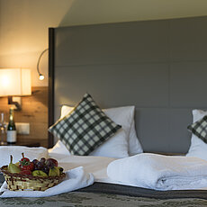 Cozy hotel room with double bed, fresh towels and fruit basket on blanket
