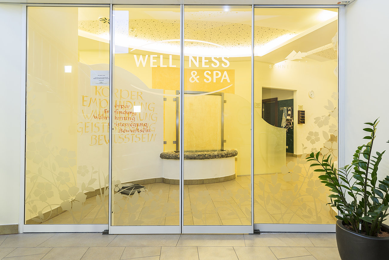 Eingang zum Wellness- und Spa-Bereich mit Milchglastüren und Zimmerpflanze