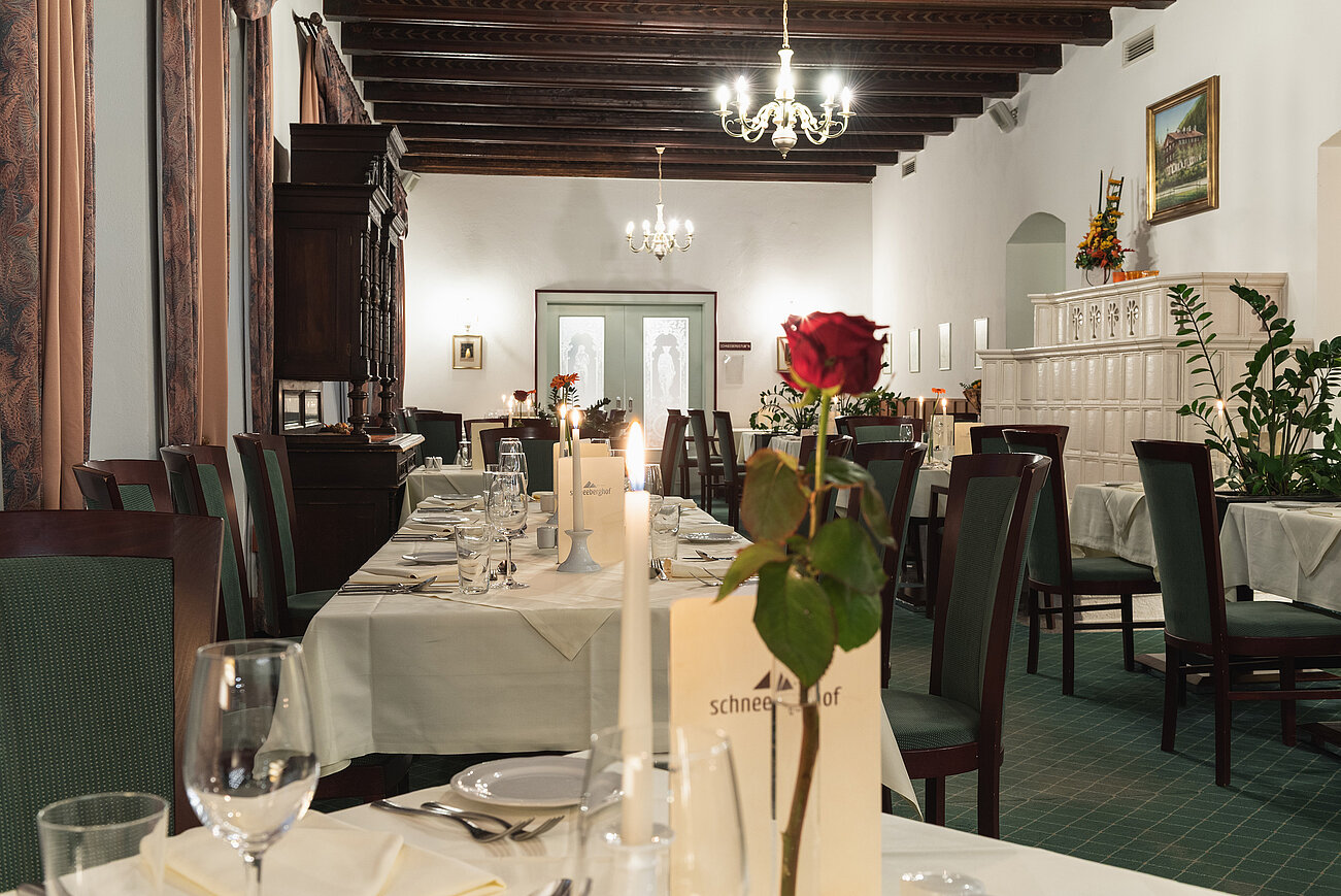 Elegantes Restaurant mit gedeckten Tischen, Rosen als Tischdeko und warmer Beleuchtung