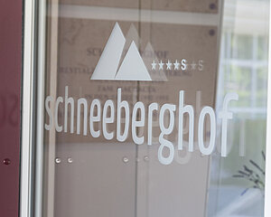 Schneeberghof Hotel-Logo mit Bergsymbol und Sternebewertung auf Glaseingangstür
