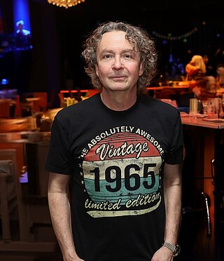 Mann mit schwarzem Vintage-1965-Limited-Edition-T-Shirt in einem schummrig beleuchteten Restaurant