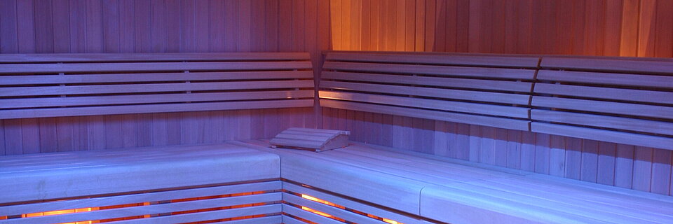 Moderne Sauna aus Holz mit gestuften Bänken und stimmungsvoller Beleuchtung