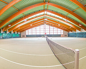 Zwei Personen spielen Tennis auf einem Indoorplatz mit gewölbter Holzdecke