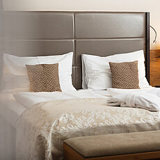 Cozy hotel room with double bed, patterned pillows, bathrobes, and warm bedside lighting