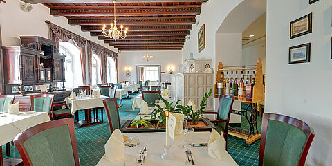 Elegantes Restaurant mit Vintage-Dekor, grünem Teppich und ordentlich gedeckten Tischen