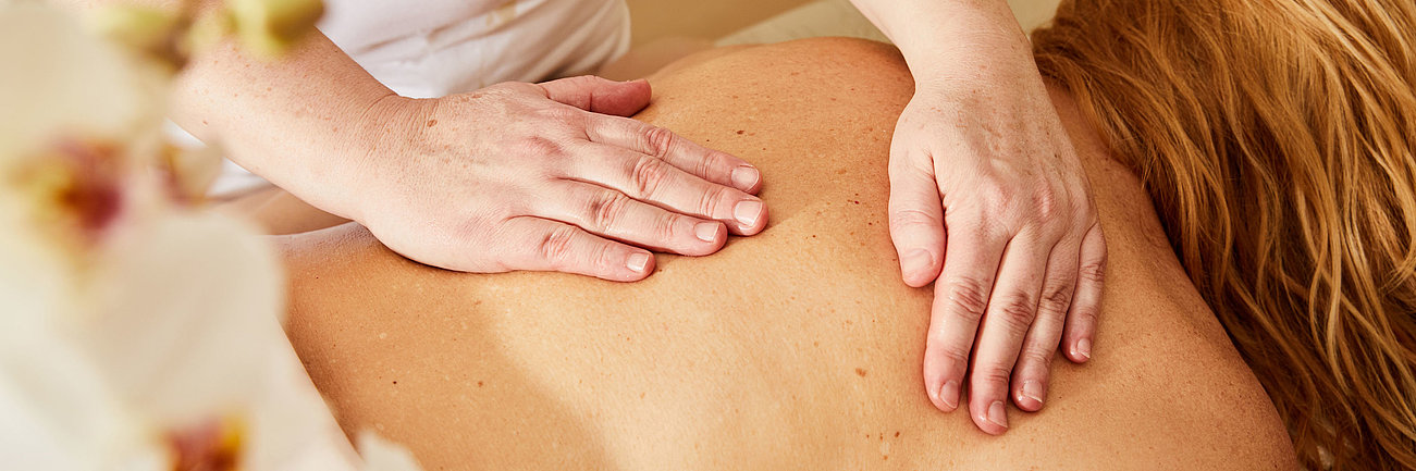 Frau erhält eine entspannende Rückenmassage in einem Spa mit warmem Licht