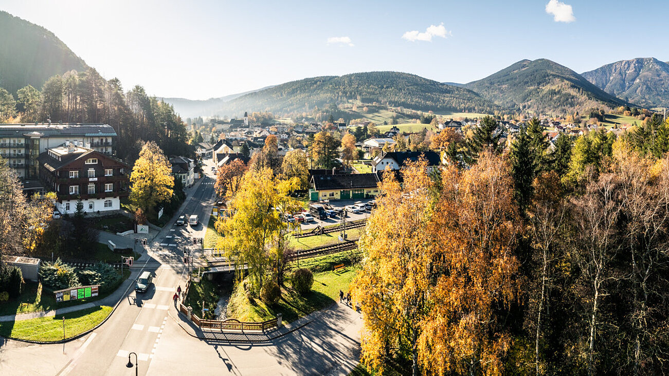 Panoramablick auf ein Dorf zwischen bewaldeten Bergen im Herbst