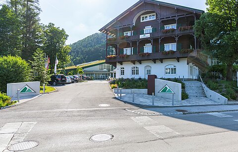 Traditionelles Hotel im Alpenstil mit Blumenbalkonen und Bergblick unter klarem Himmel