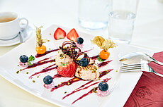 Gourmet-Dessert mit Mousse, Erdbeeren, Heidelbeeren und Sauce elegant auf weißem Teller angerichtet