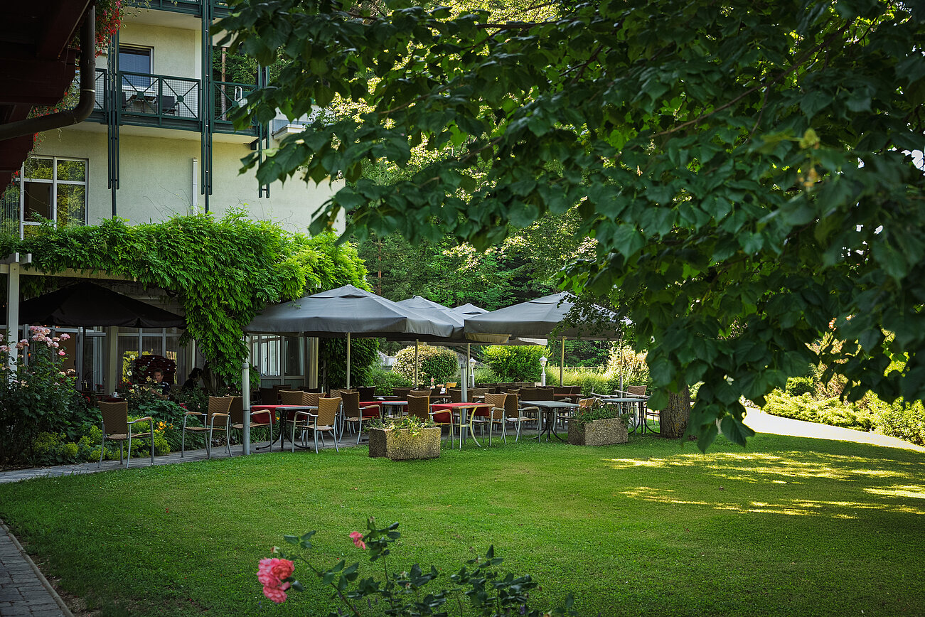 Sitzgelegenheiten im Freien mit Sonnenschirmen in einem grünen Garten