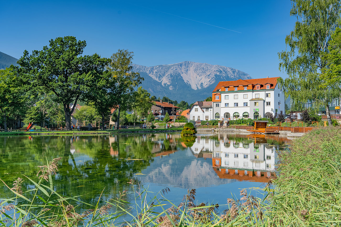 Malerischer Seeblick mit Hotel, grünen Bäumen und Bergen im Hintergrund