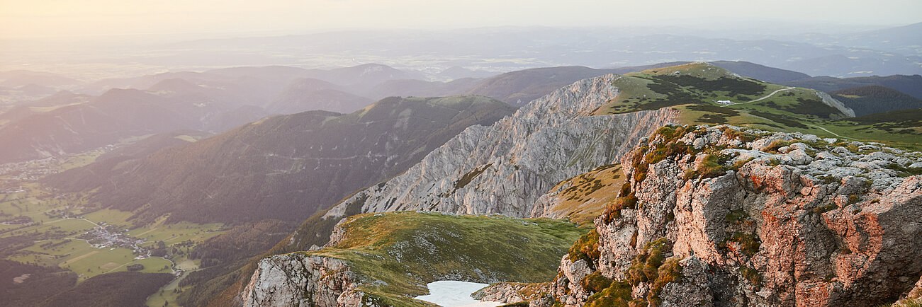 Rocky mountain landscape with grassy peaks and distant valley at sunset