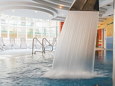 Innenpool mit Wasserfall-Feature und Liegestühlen