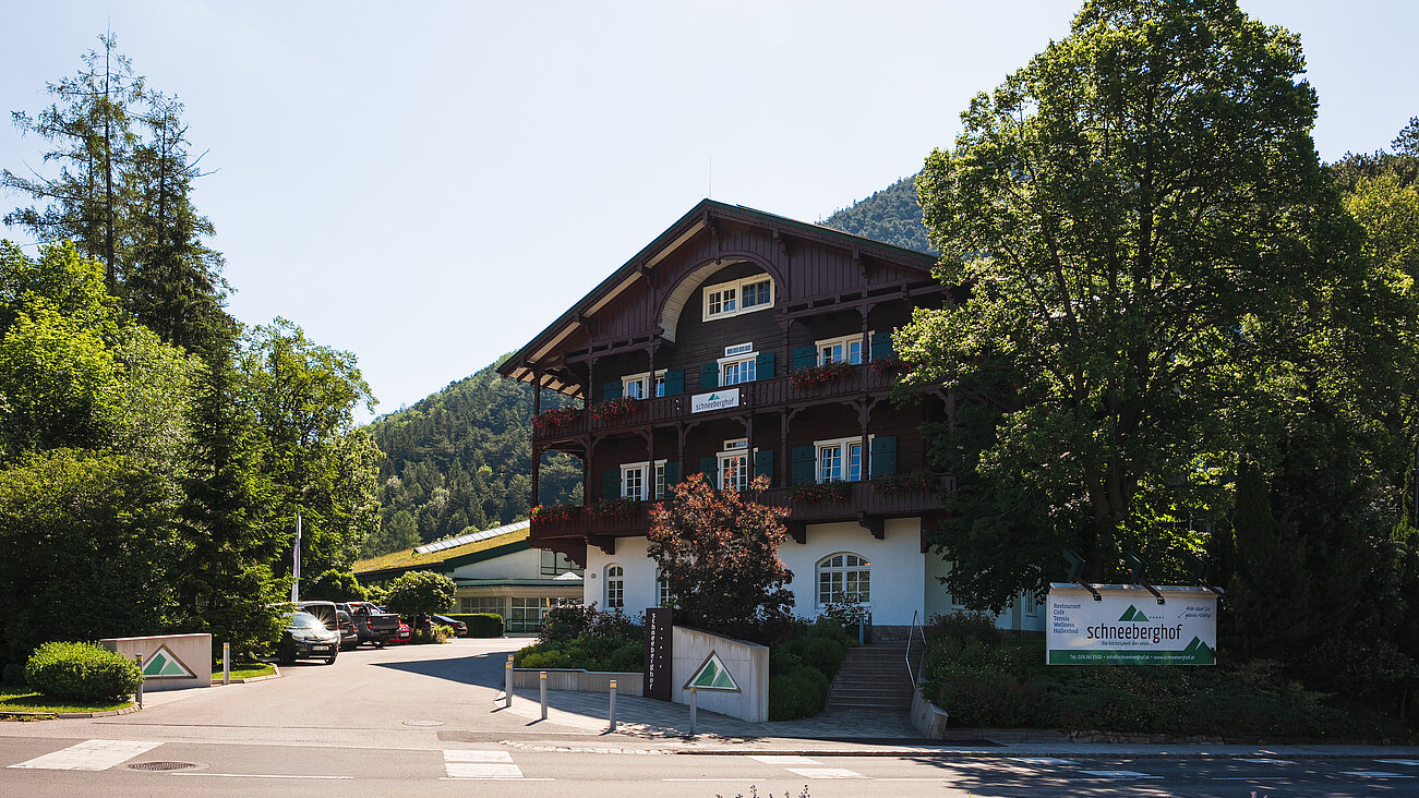 Holzgebäude mit grünen Fensterläden umgeben von Bäumen an einem sonnigen Tag