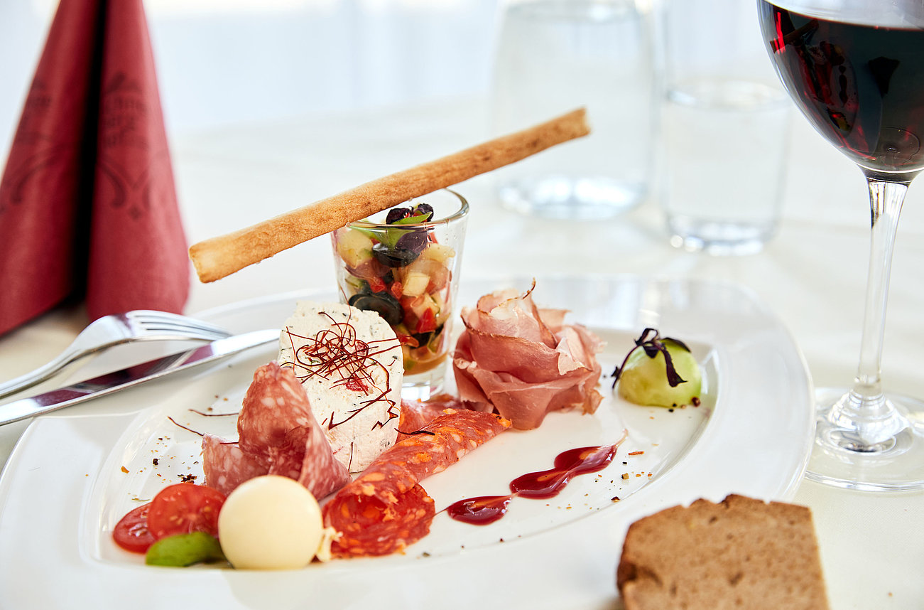 Gourmet antipasto platter with cured meats, cheese, vegetable salad and red wine