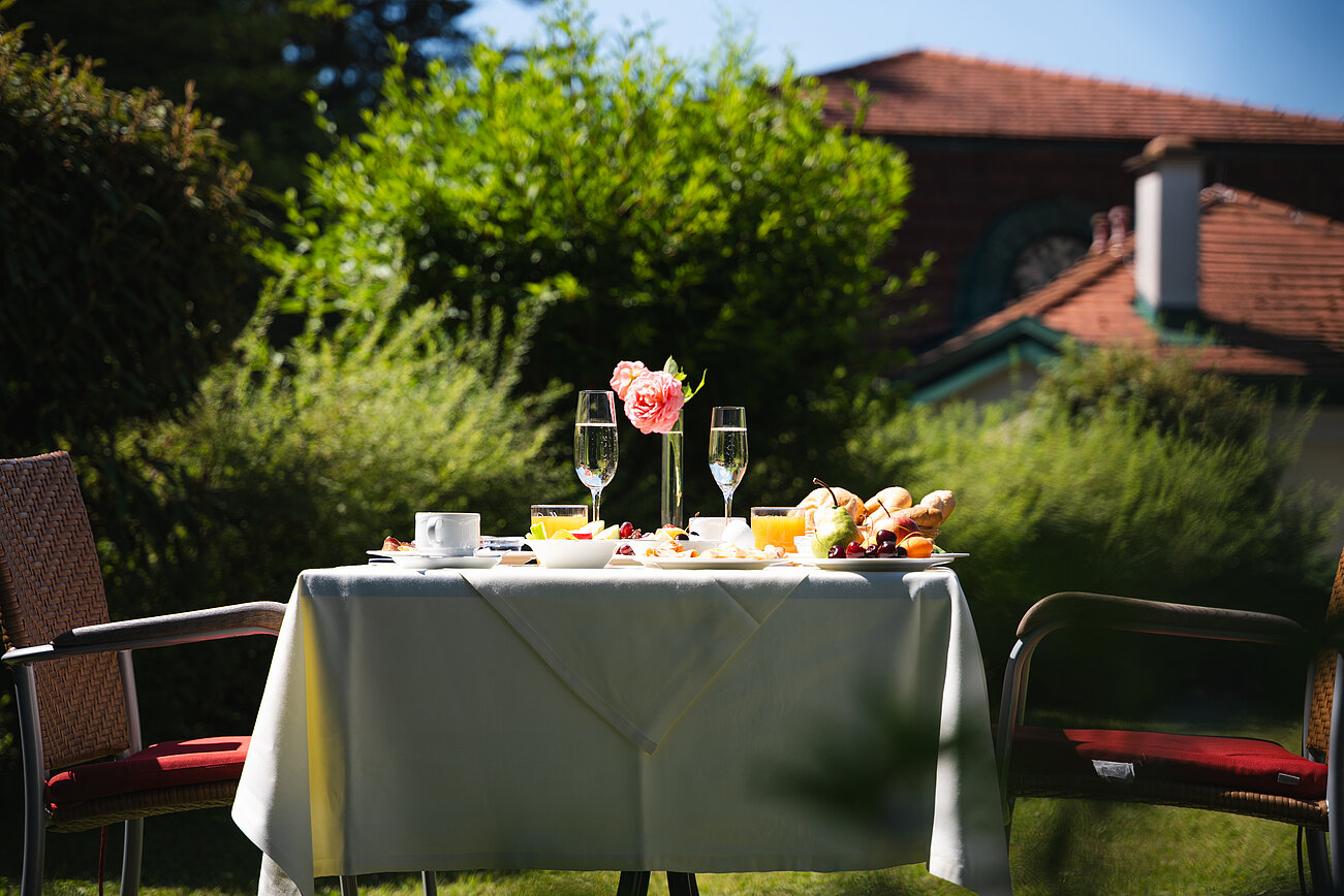 Outdoor dining table set for breakfast with flowers, drinks, and pastries