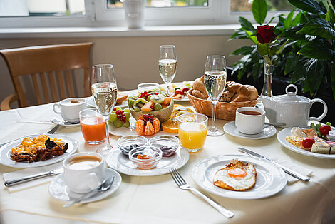 Luxuriöser Frühstückstisch mit Obst, Eiern, frischen Säften, Gebäck und Champagner