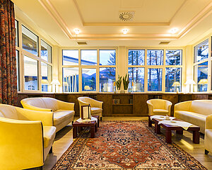 Gemütliche Hotellounge mit Ledersesseln, großen Fenstern und warmer Beleuchtung