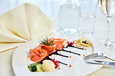 Gourmet-Räucherlachs mit Balsamico-Glasur, Zitronenscheiben, Gurke und Dill auf weißem Teller