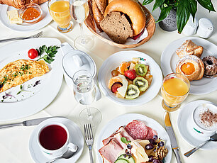 Luxuriöses Hotelfrühstück mit Omelett, Aufschnitt, Obst, Gebäck, Saft, Tee und Kaffee